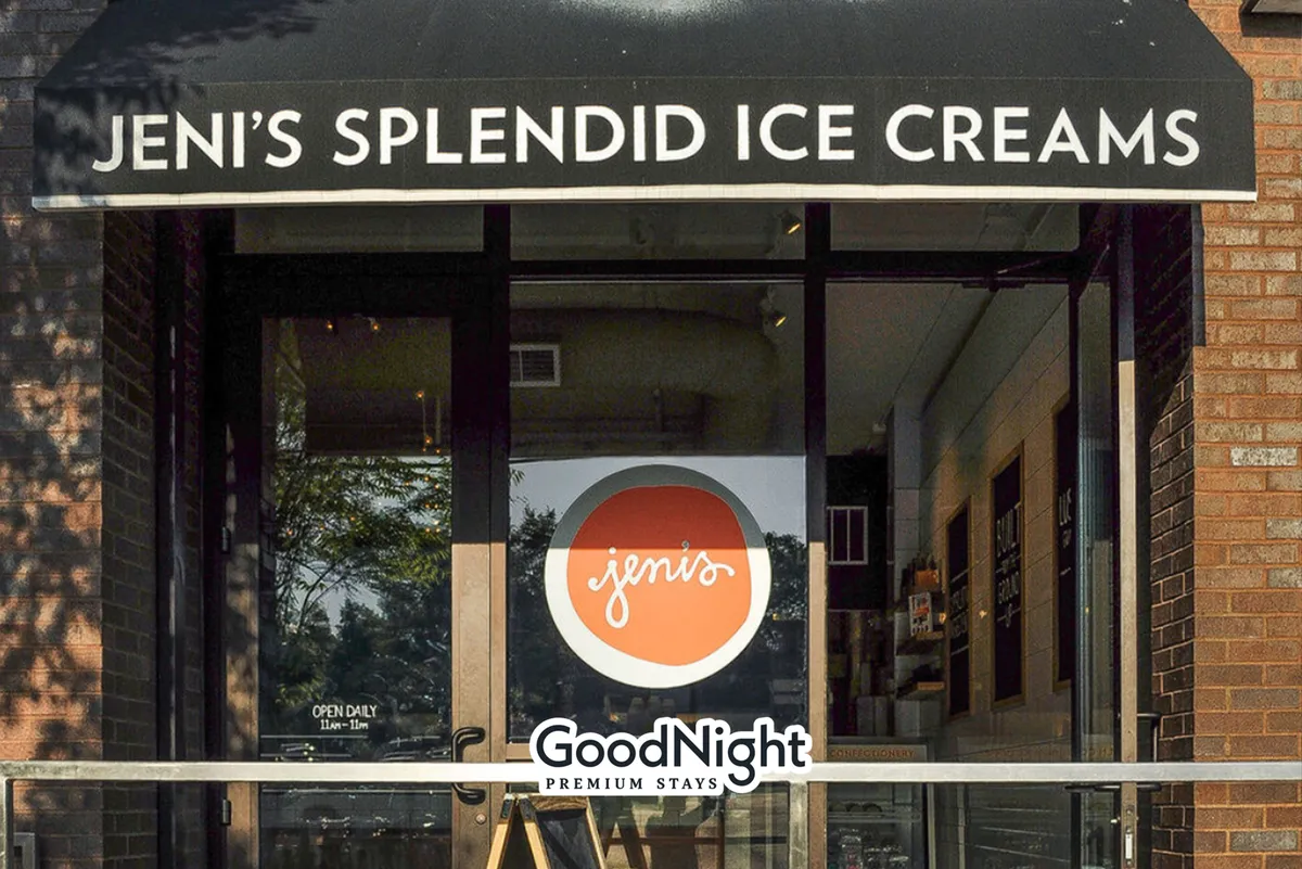 A cheerful storefront with an awning and clear signage, set against a bright backdrop. Groups gather outside, enjoying ice cream and each other's company in a sociable, friendly atmosphere.