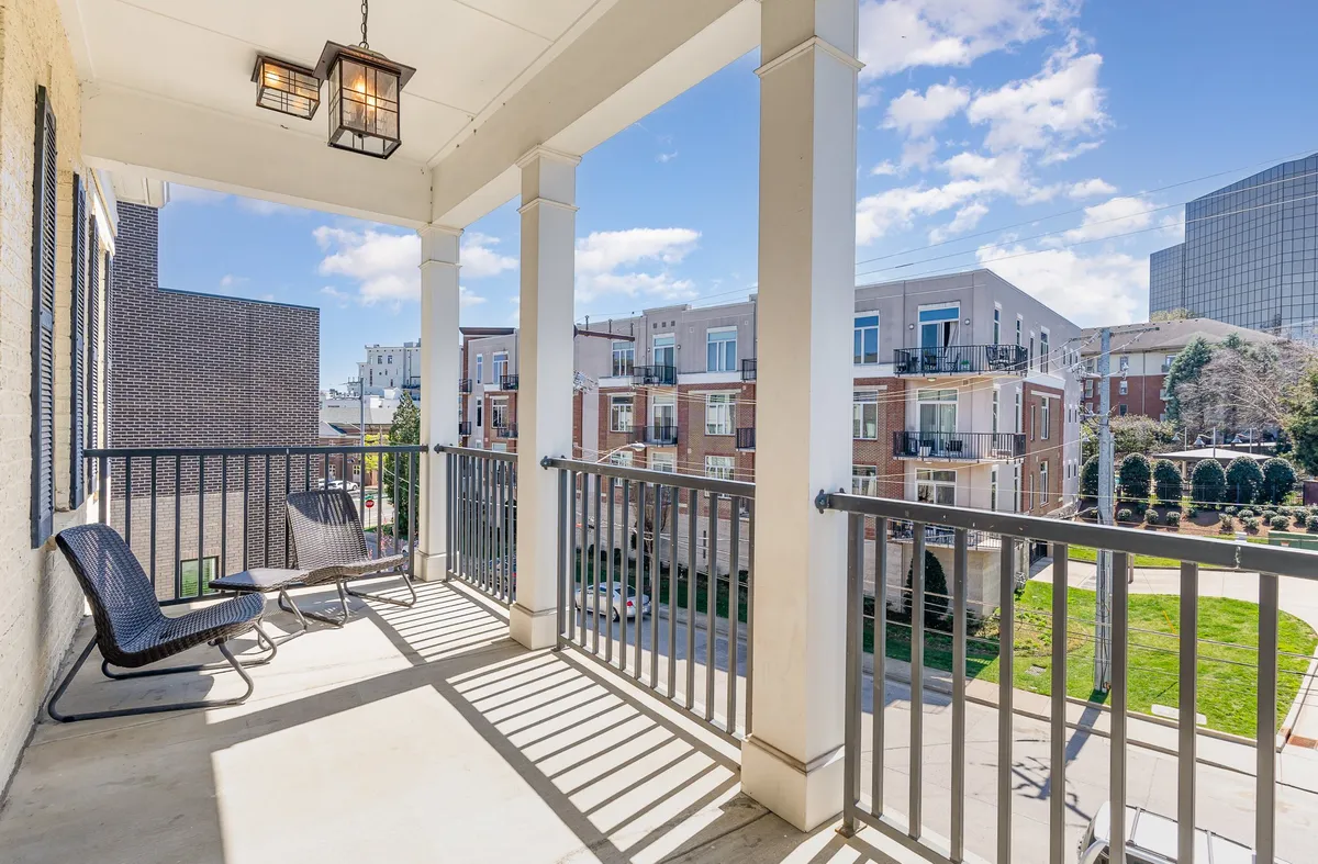 A private balcony scene featuring a chic railing, hanging light fixture, and outdoor seating. The balcony invites residents to enjoy morning coffee, unwind with a book, or socialize while overlooking the city skyline.