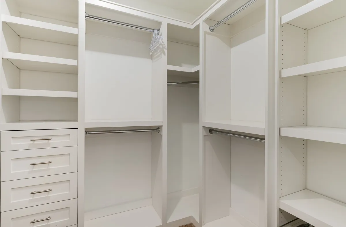 A minimalistic and highly functional walk-in closet featuring open shelving, hanging rods, and organized drawers—ideal for storing clothes and accessories while keeping the space clutter-free.