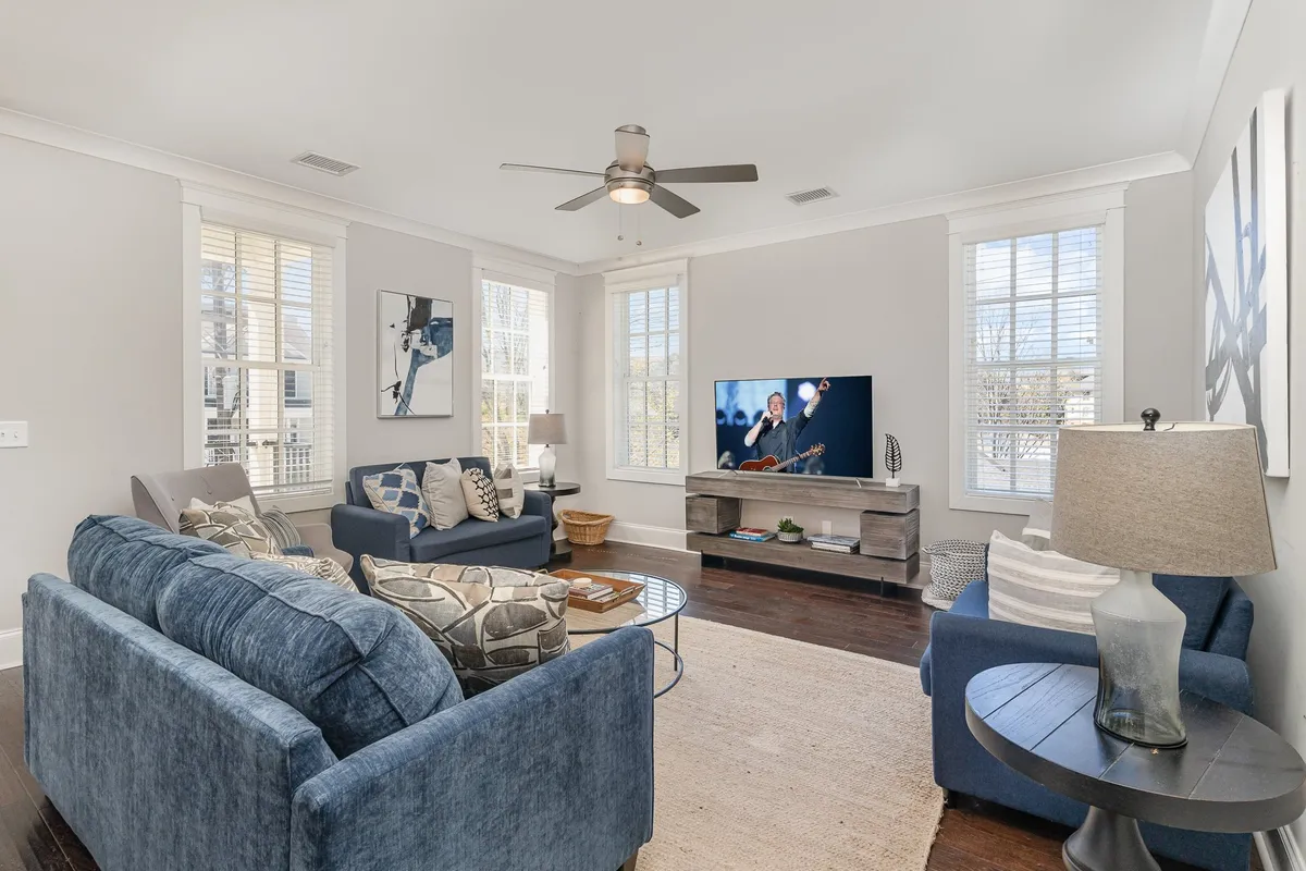 The image shows a stylish and inviting living room with a plush sofa, a modern coffee table, a large flat-screen television, and vibrant artwork adorning the wall. The room is bathed in warm, natural light, creating a cozy and welcoming atmosphere perfect for relaxing or entertaining guests.