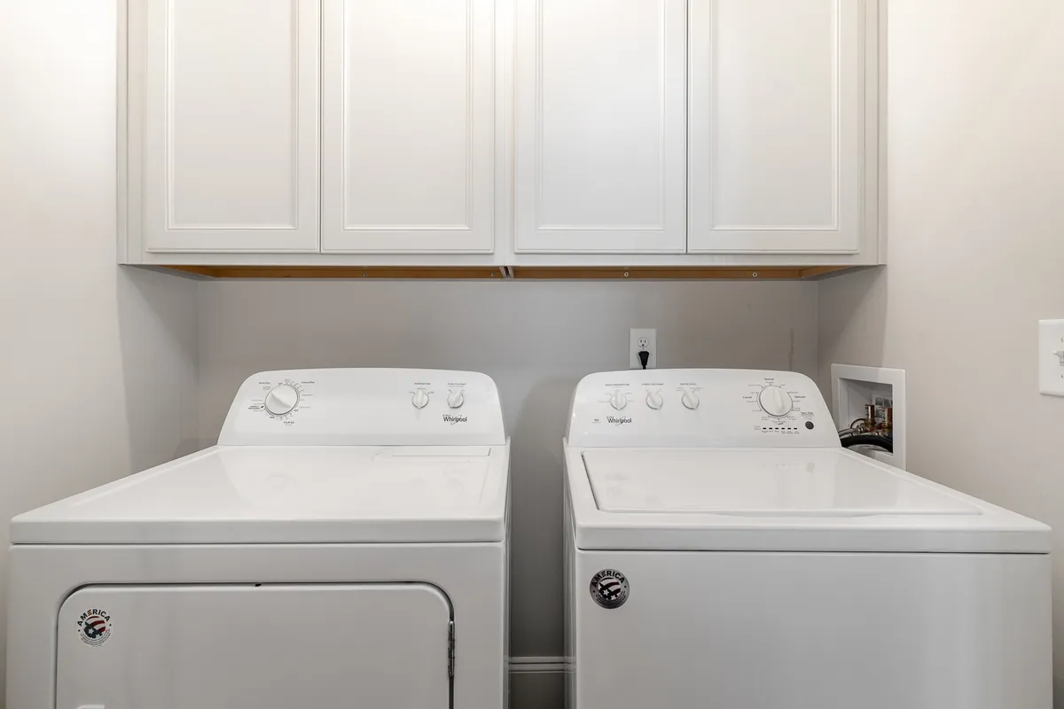 A dedicated laundry area with a modern washing machine, dryer, and ample cabinetry for storage, providing a sense of efficiency and organization.