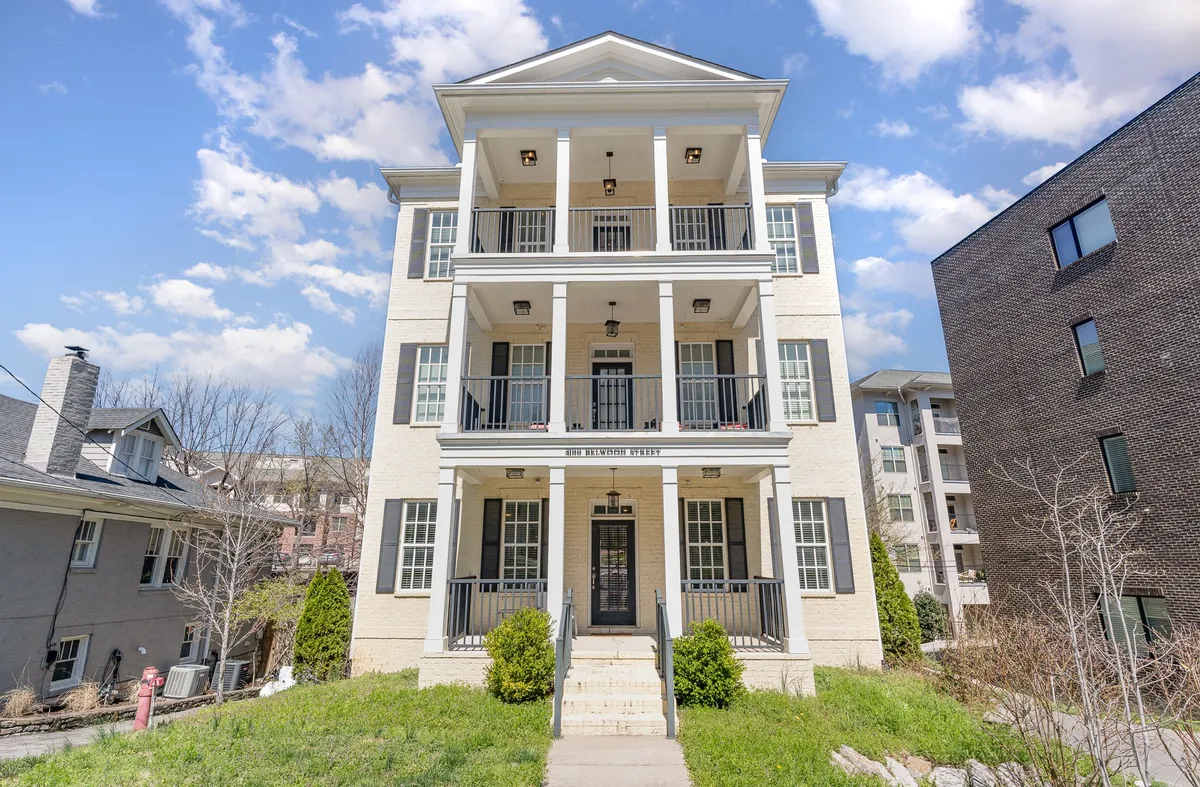 This image captures the three-story facade of Belwood Manor, featuring balconies with railings and a welcoming entrance staircase. The overall architecture is modern and symmetrical, inviting guests to imagine arriving at or departing from the property. The balconies and exterior spaces hint at opportunities for relaxation and informal gatherings.
