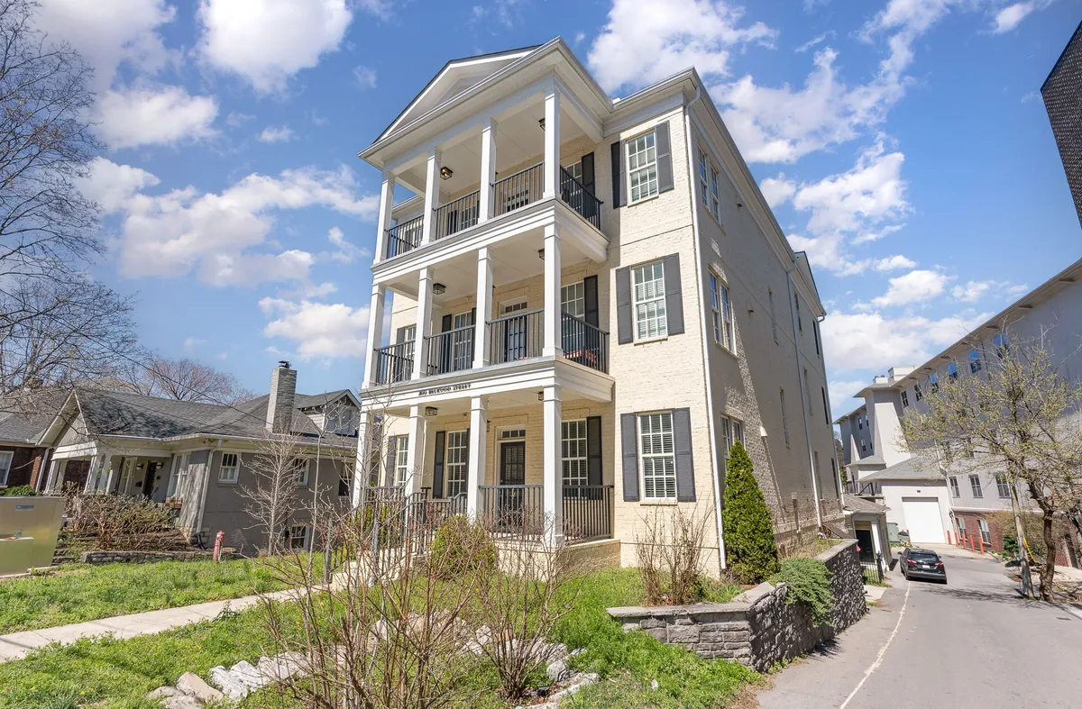 A three-story residential building featuring welcoming balconies with railings, front steps, and a landscaped entrance. The balconies provide a private outdoor perch above the lively Midtown scene.