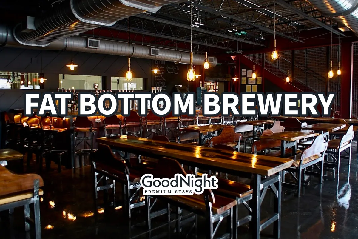 A bustling, modern bar with a long wooden counter, hanging Edison bulbs, and an open seating arrangement. People are socializing, enjoying craft brews, and soaking in the casual, vibrant ambiance.